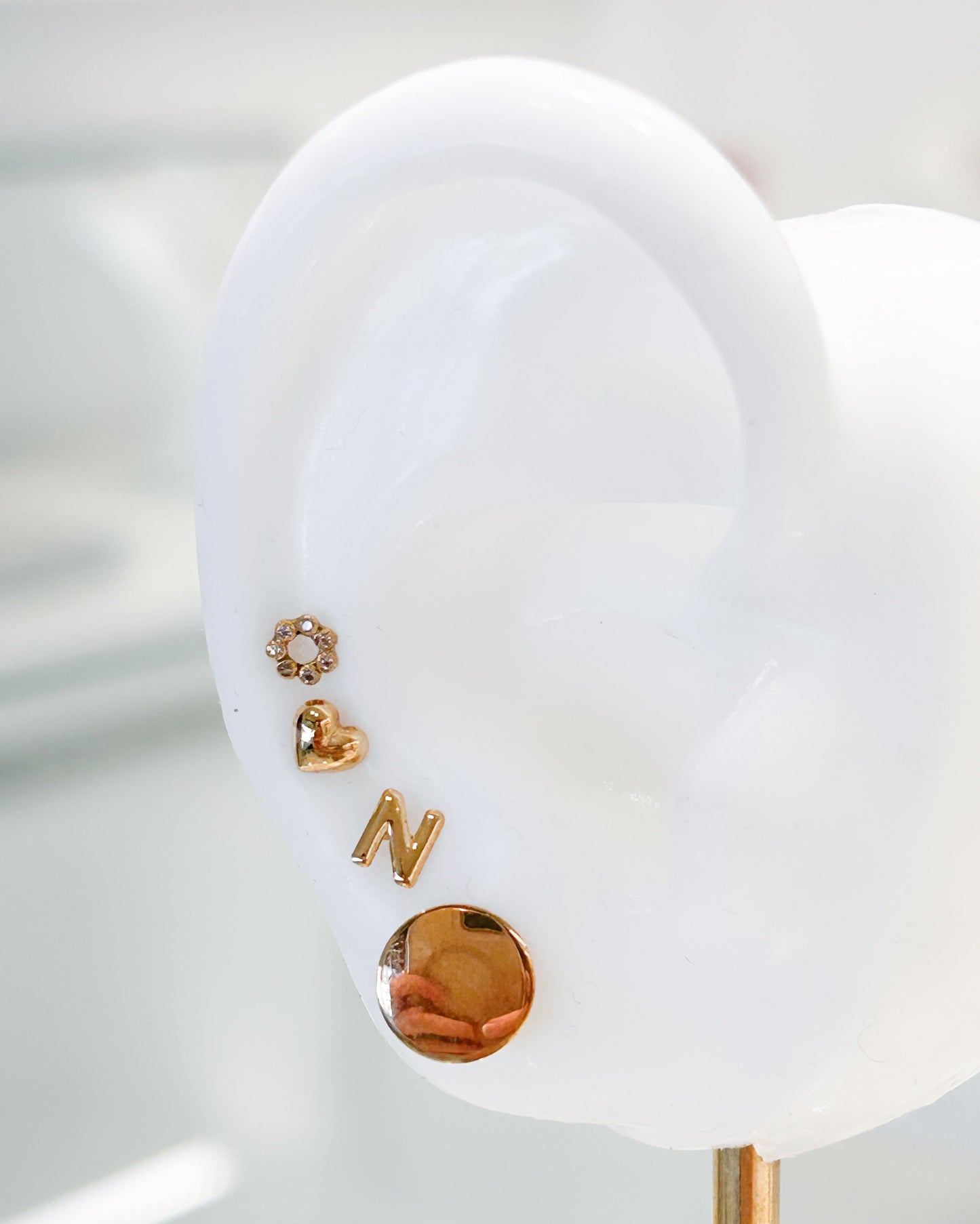 Arete tipo broquel de inicial "N" miniatura en oro 10k