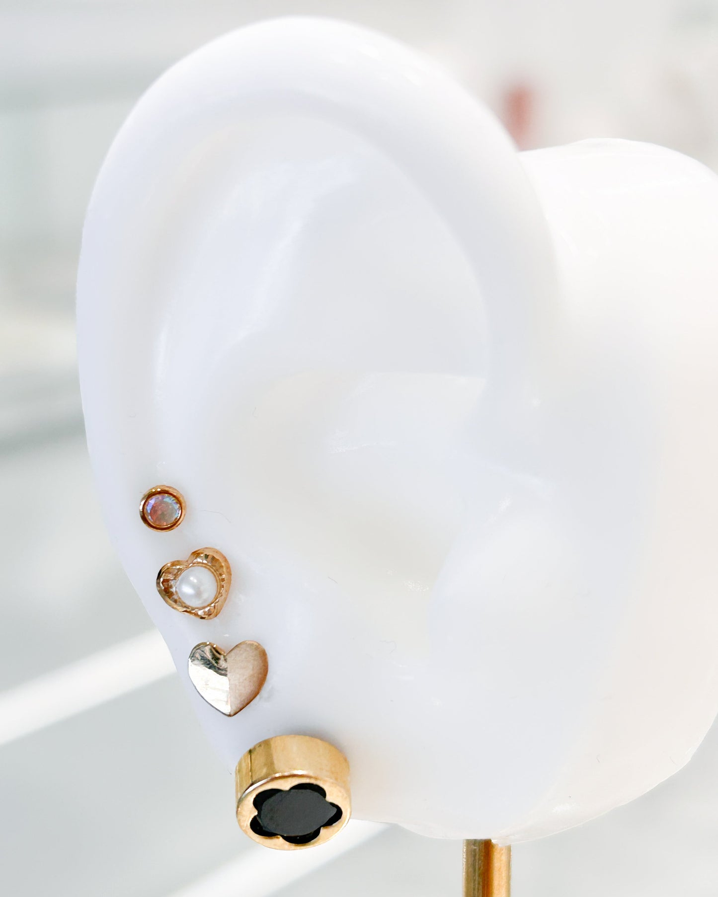 Arete tipo broquel circular con silueta de flor y fondo negro en oro 10k