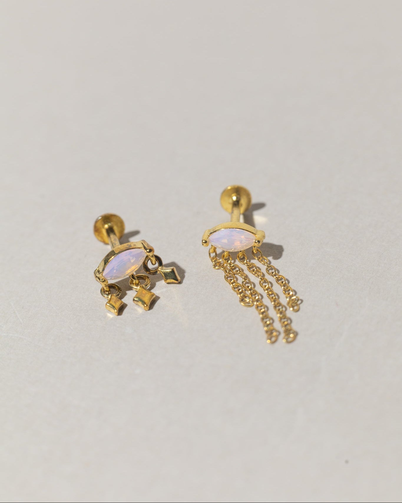Aretes asimétricos con cristales rosados y cadenas de flecos dorados