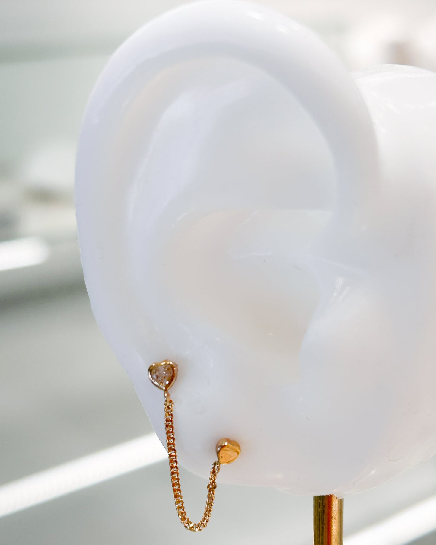Arete tipo broquel de doble corazón con cadena de eslabones y detalles en cristal