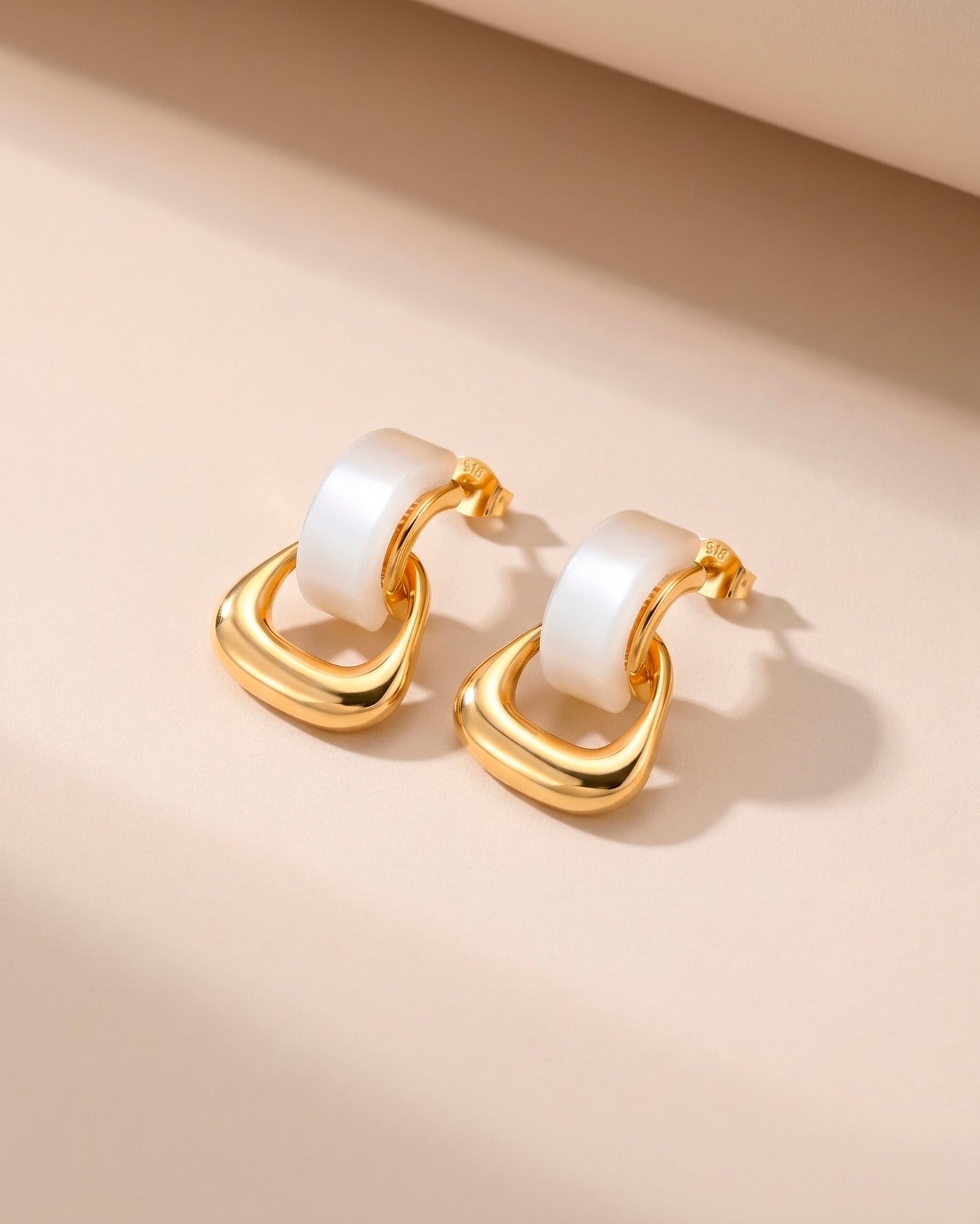 Aretes tipo studs con aros entrelazados en dorado y blanco