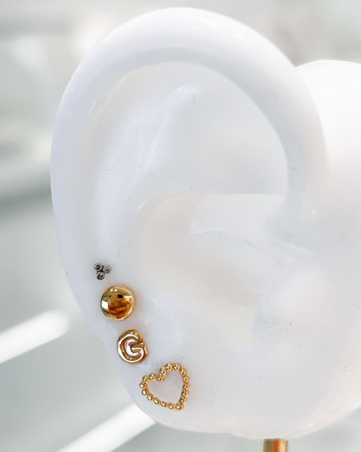 Arete tipo broquel de inicial "G" miniatura en oro 10k