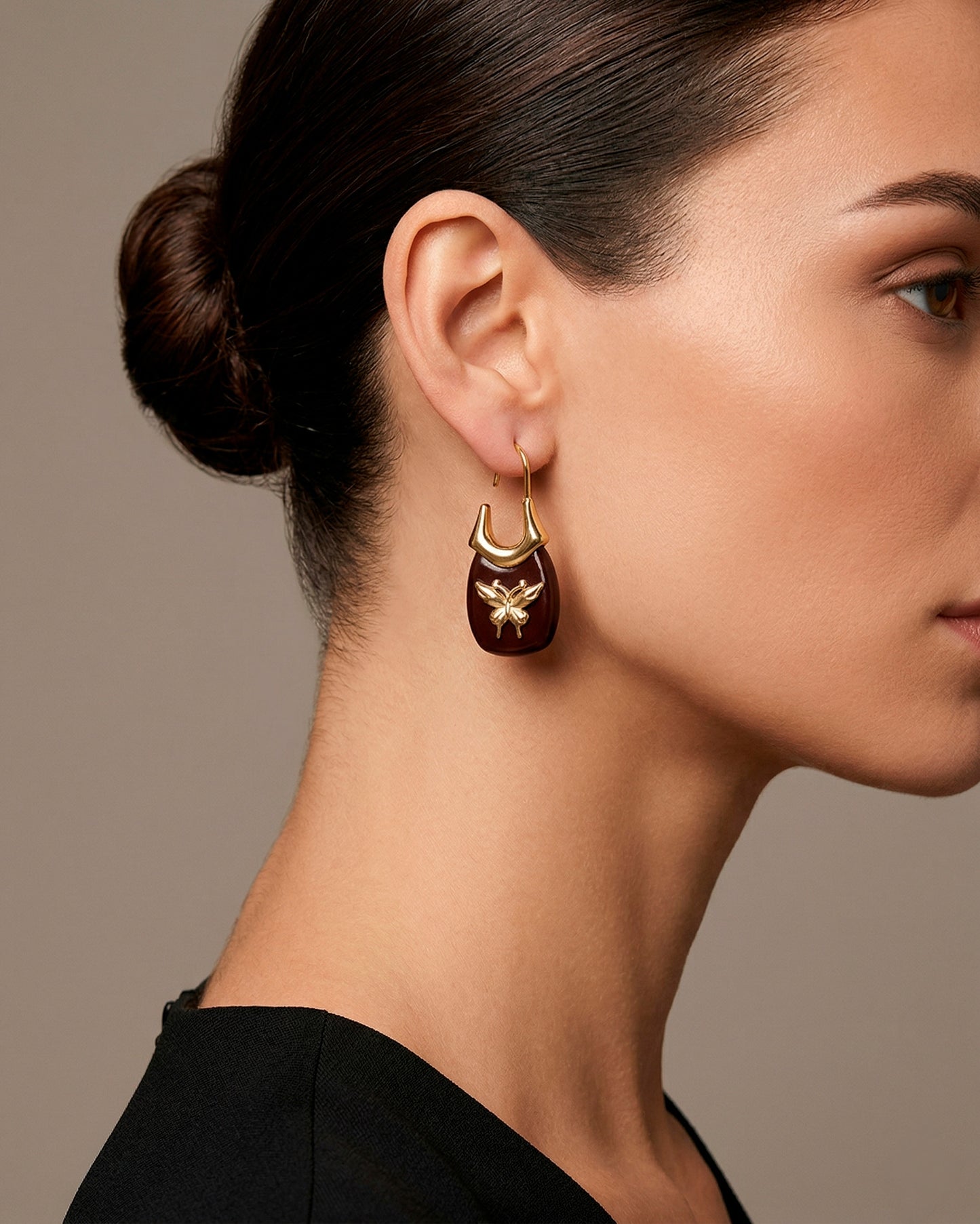 Aretes dorados estilo arracada con piedra negra y diseño de mariposa