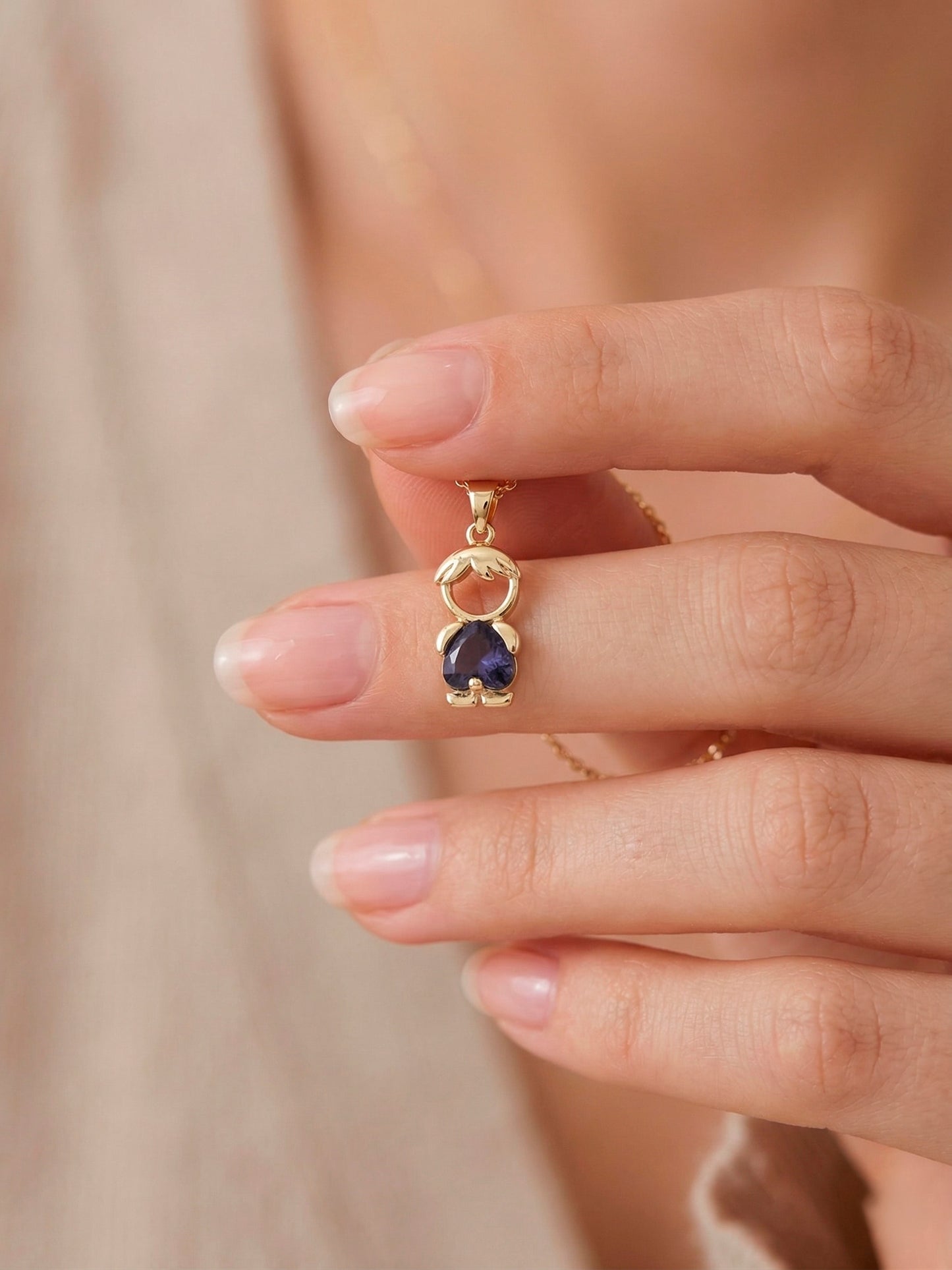 Dije de silueta de niño dorado con cuerpo de cristal azul zafiro
