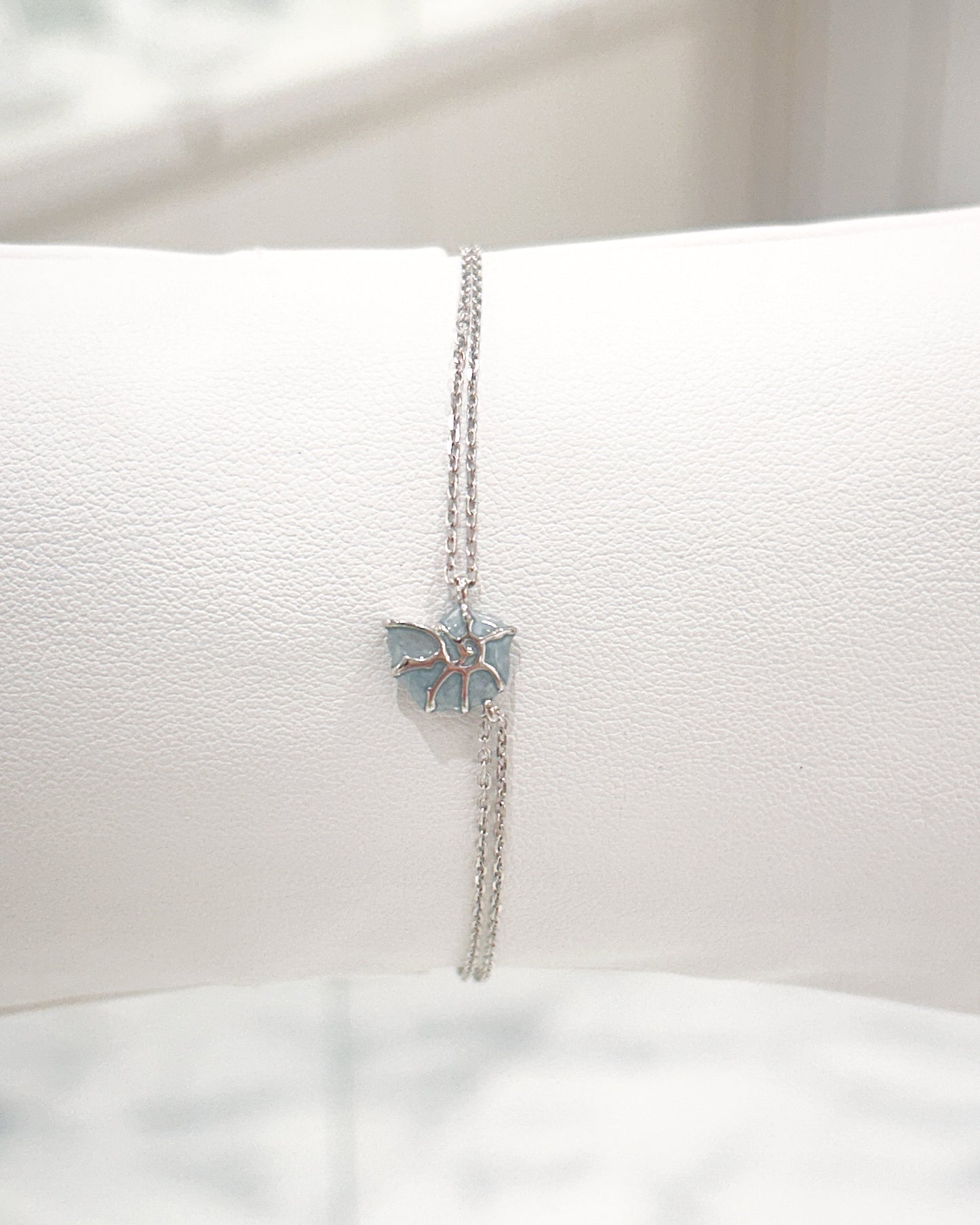 Pulsera de doble cadena con detalle de caracol y deposito de color azul mar y plata