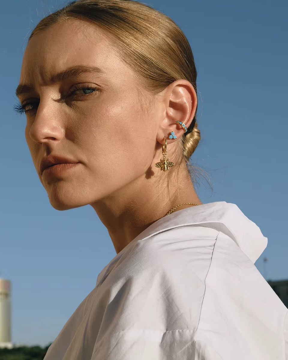 Arete dorado con piedras color turquesa, de tipo ear cuff.