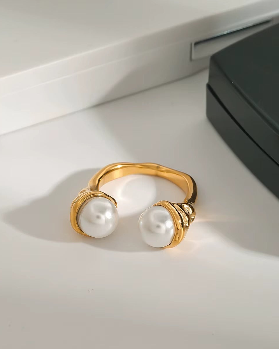 Anillo dorado de perlas, de tipo ajustable.