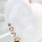 Arete tipo broquel circular con silueta de flor y fondo negro en oro 10k