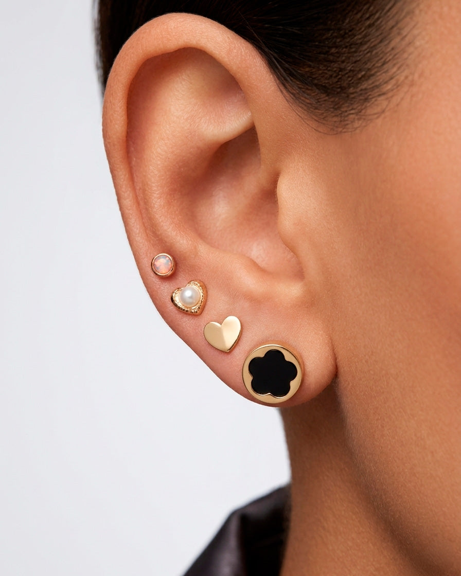 Arete tipo broquel circular con silueta de flor y fondo negro en oro 10k