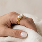 Anillo dorado de perlas, de tipo ajustable.