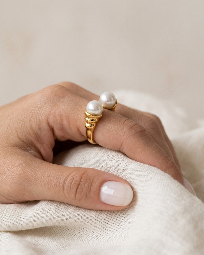Anillo dorado de perlas, de tipo ajustable.