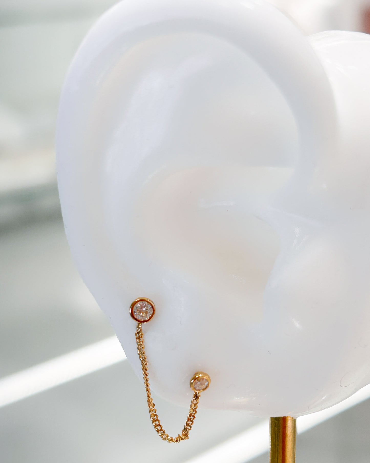 Arete tipo broquel de doble punto con cadena colgante y circonias