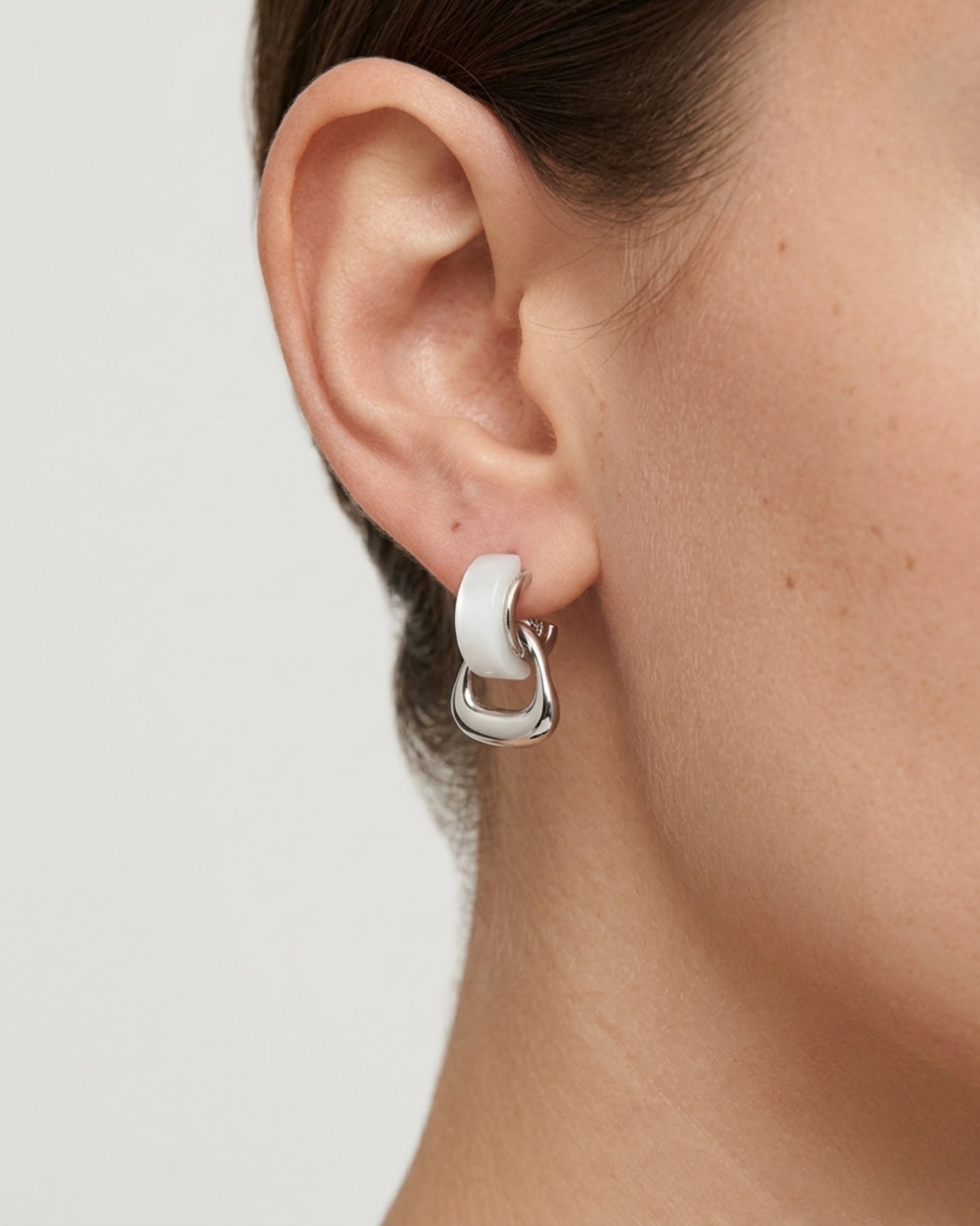 Aretes tipo studs con aros entrelazados en plateado y blanco