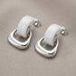 Aretes tipo studs con aros entrelazados en plateado y blanco