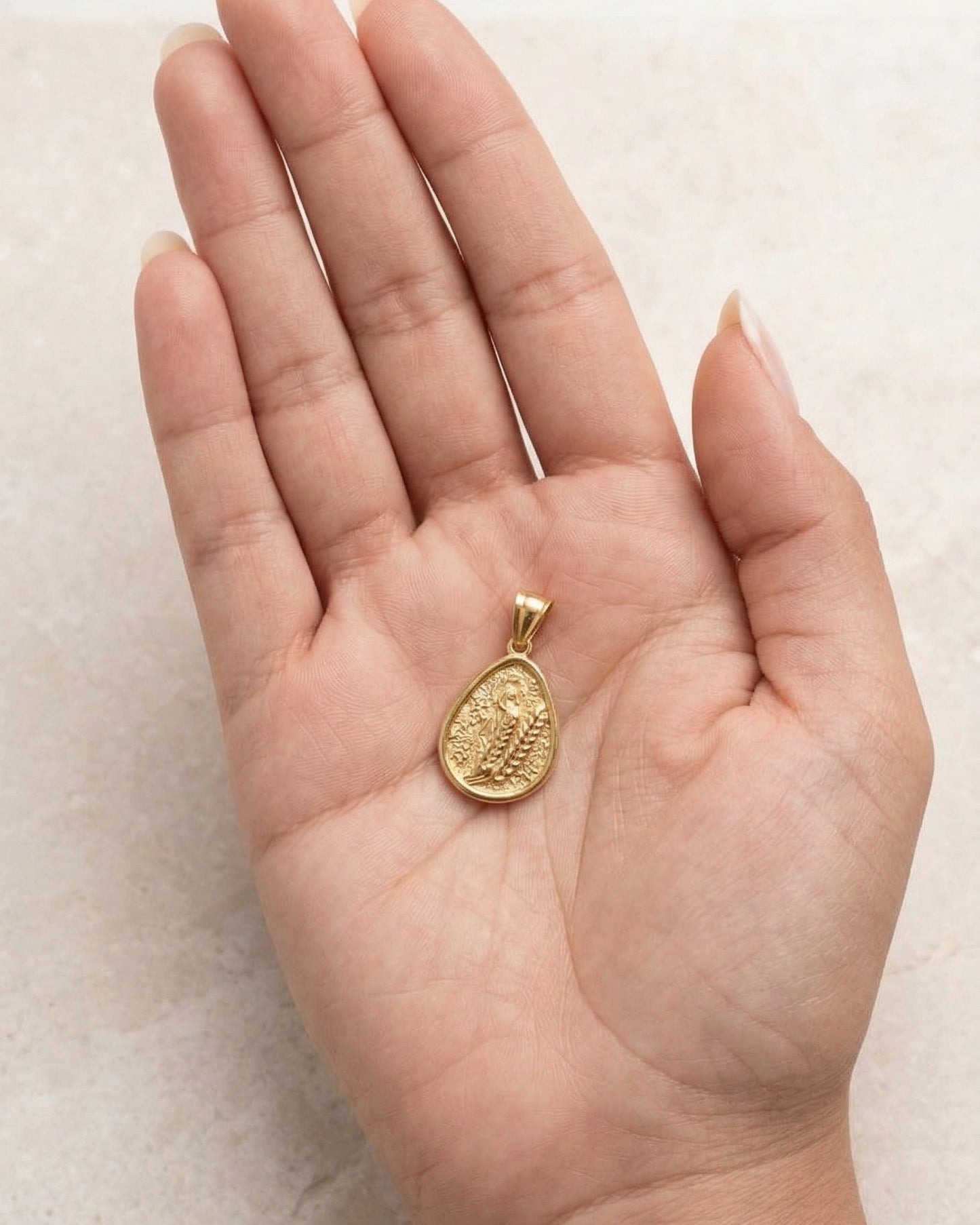Dije medallón dorado en forma de gota con bajorrelieve abstracto