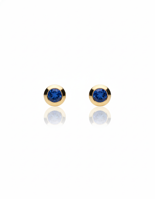 Arete tipo broquel con zirconias color azul con bisel circular en oro 10k