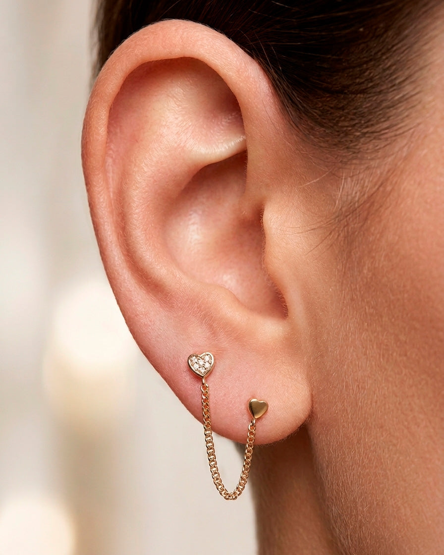 Arete tipo broquel de doble corazón con cadena de eslabones y detalles en cristal