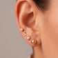 Arete tipo broquel de conchita de mar con textura en relieve en oro 10k