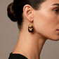 Aretes dorados estilo arracada con piedra negra y diseño de mariposa