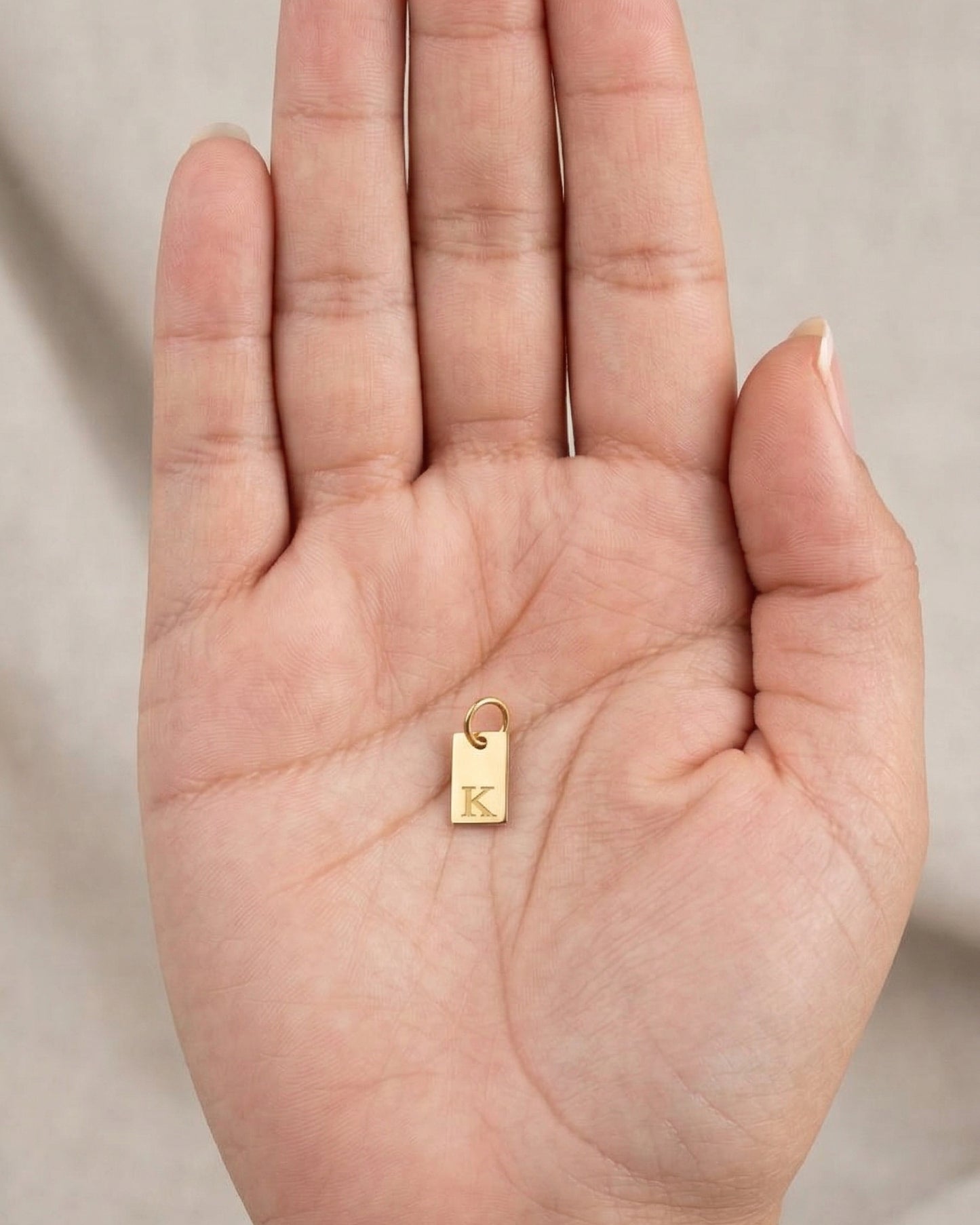 Dije de placa rectangular dorada con inicial grabada