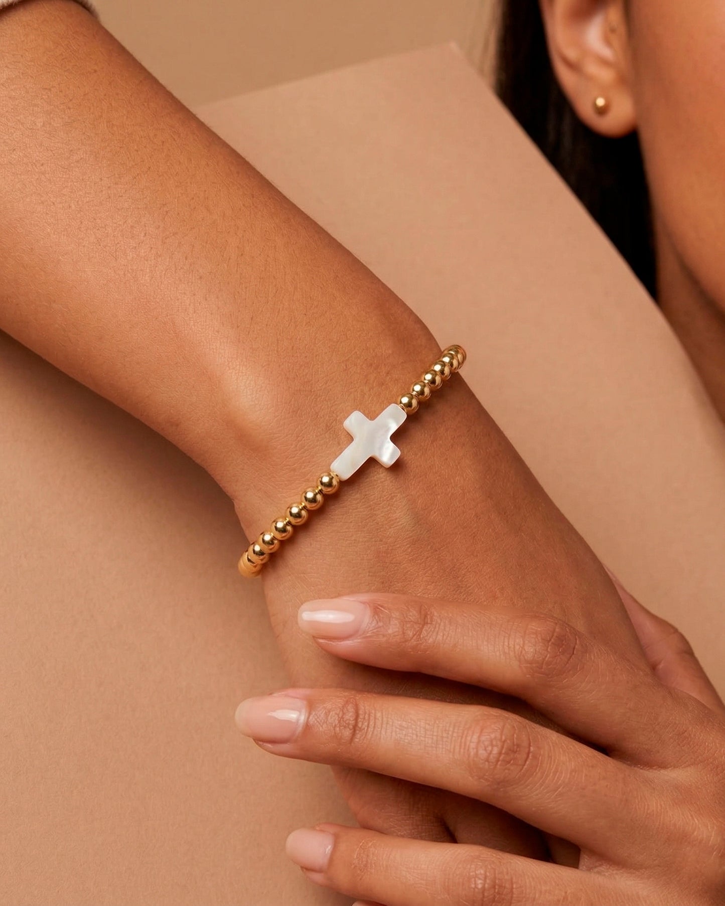 Pulsera dorada con diseño de cruz en perla