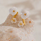 Aretes con diseño de flores blancas tipo studs dorado