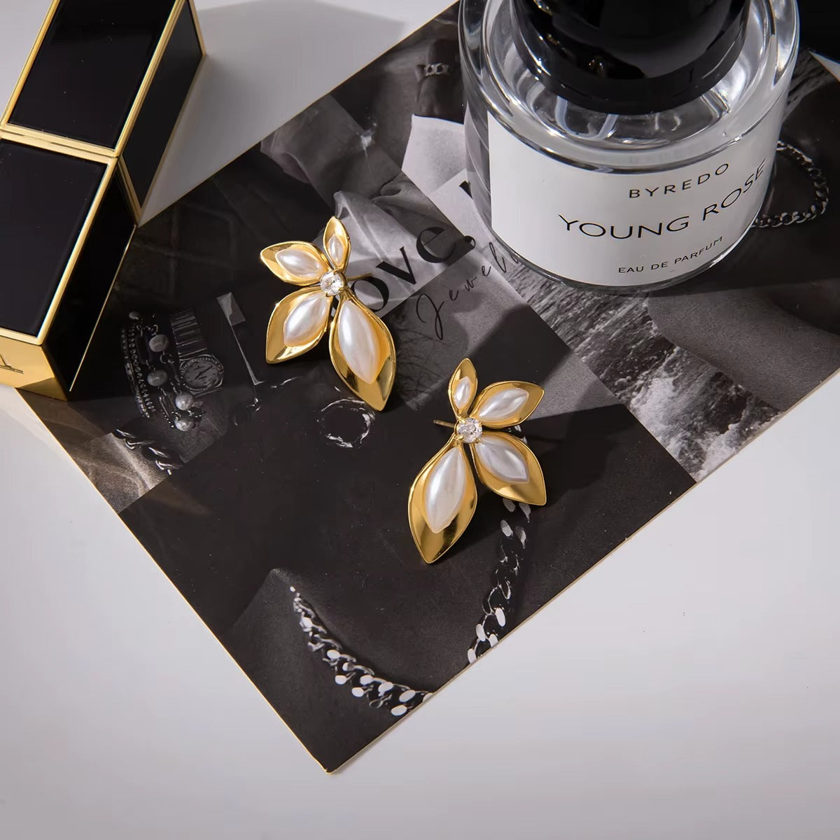 Arete de flor en color blanco y dorado, de tipo studs.