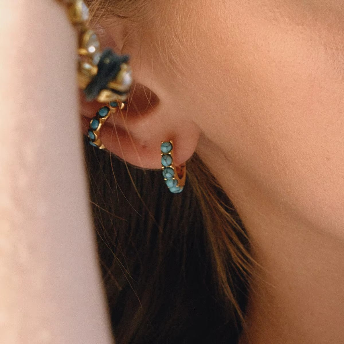 Arete dorado con piedras color turquesa, de tipo ear cuff.