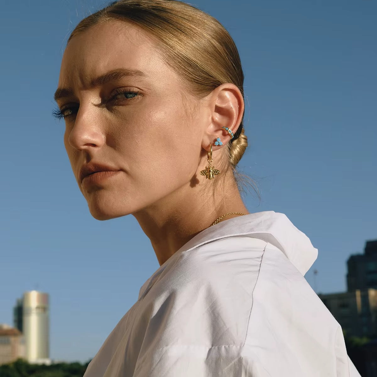 Arete dorado con piedras color turquesa, de tipo ear cuff.