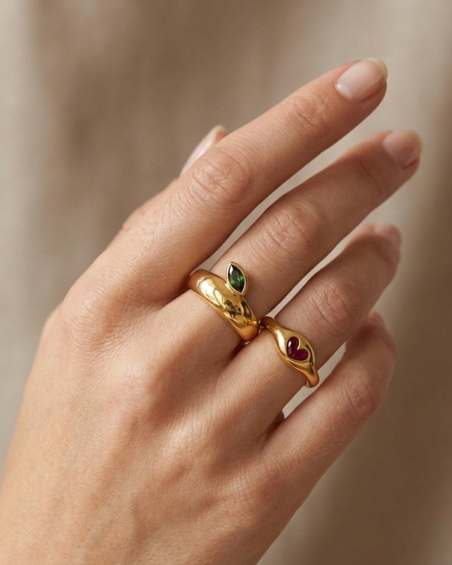 Anillo dorado con diseño de hoja color verde y corazón color rojo