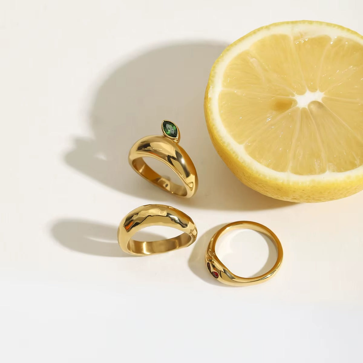 Anillo dorado con diseño de hoja y corazón, con piedra zirconia en color rojo y verde.