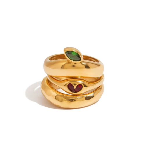 Anillo dorado con diseño de hoja y corazón, con piedra zirconia en color rojo y verde.